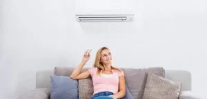 foto de mulher sentada no sofá ligando ar condicionado