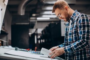 Homem trabalhando em uma gráfica com papel e tintas sabe a importância do filtros industriais para gráficas