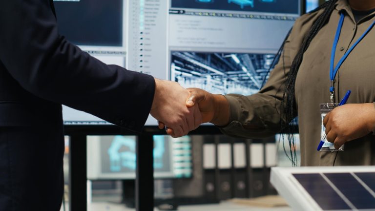 Padronização de fornecedores: um executivo apertando a mão de uma fornecedora em ambiente fabril.