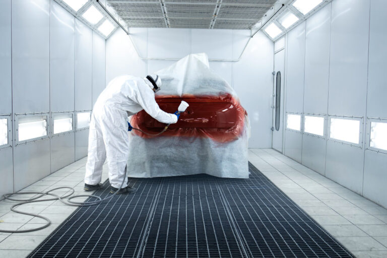 Filtro para cabine de pintura: pessoa aplicando tinta em automóvel, usando equipamento de proteção.