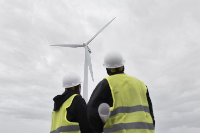 Filtro de ar para turbinas eólicas: dois técnicos de costas, diante de uma turbina eólica.
